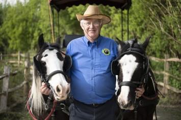 A man stood with two horses and a cart